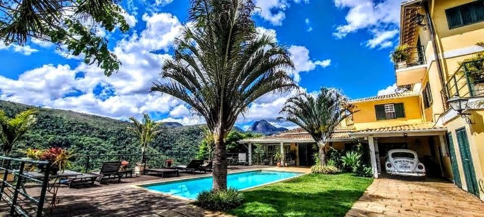 una casa con una piscina y una palmera en Pousada Quinta do Alto, en Itaipava