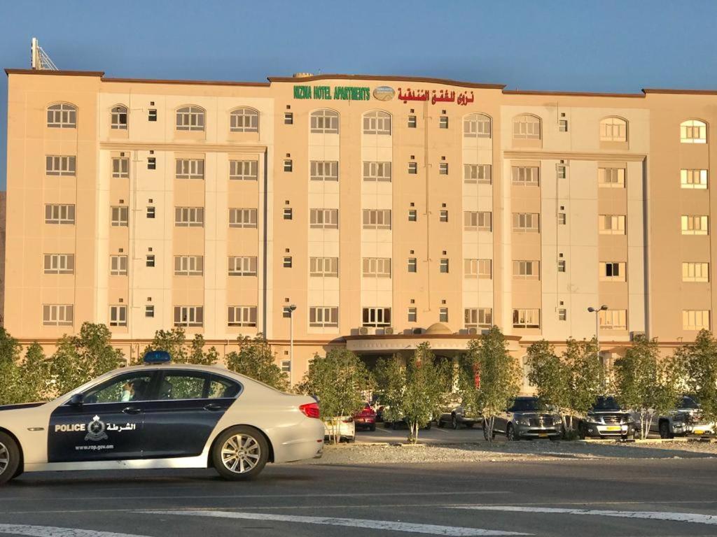 um carro estacionado em frente a um grande edifício em Nizwa Hotel Apartments em Nizwa