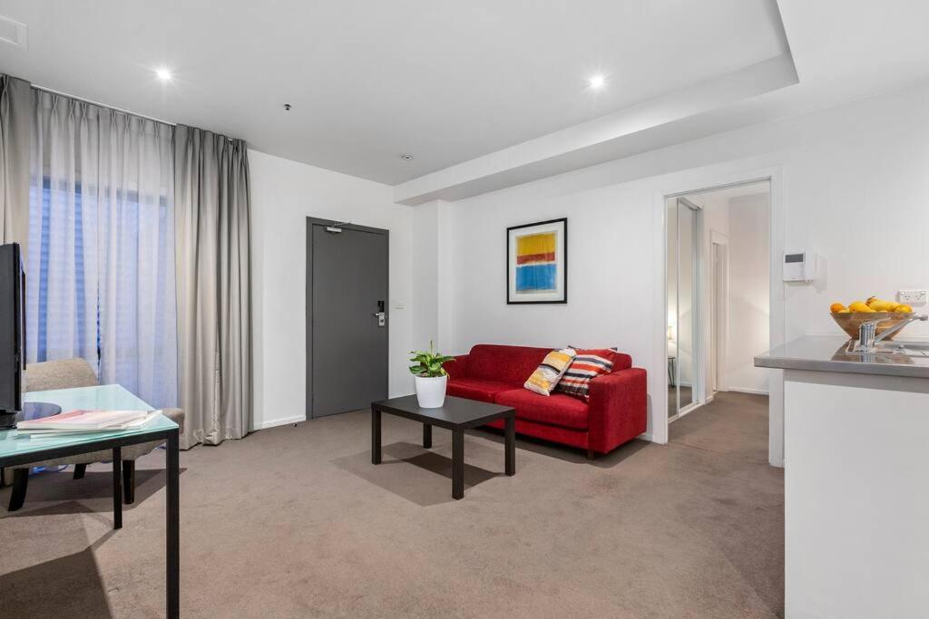 a living room with a red couch and a table at Astral Apartments. Spacious 2 bed, 2 bath apartment in a great location. in Melbourne