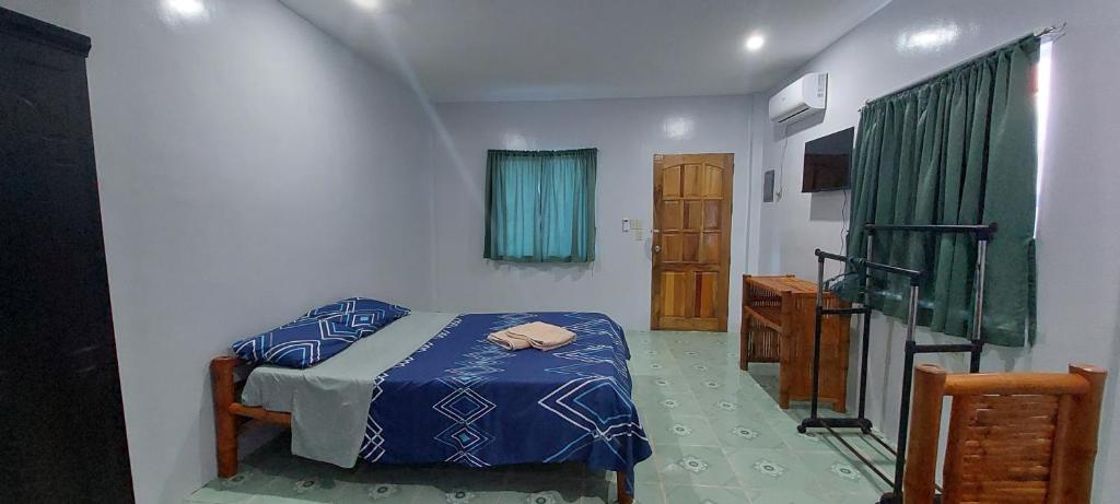 a bedroom with a bed with a blue comforter at Genna's Tourist Inn Santa Fe in Bantayan Island