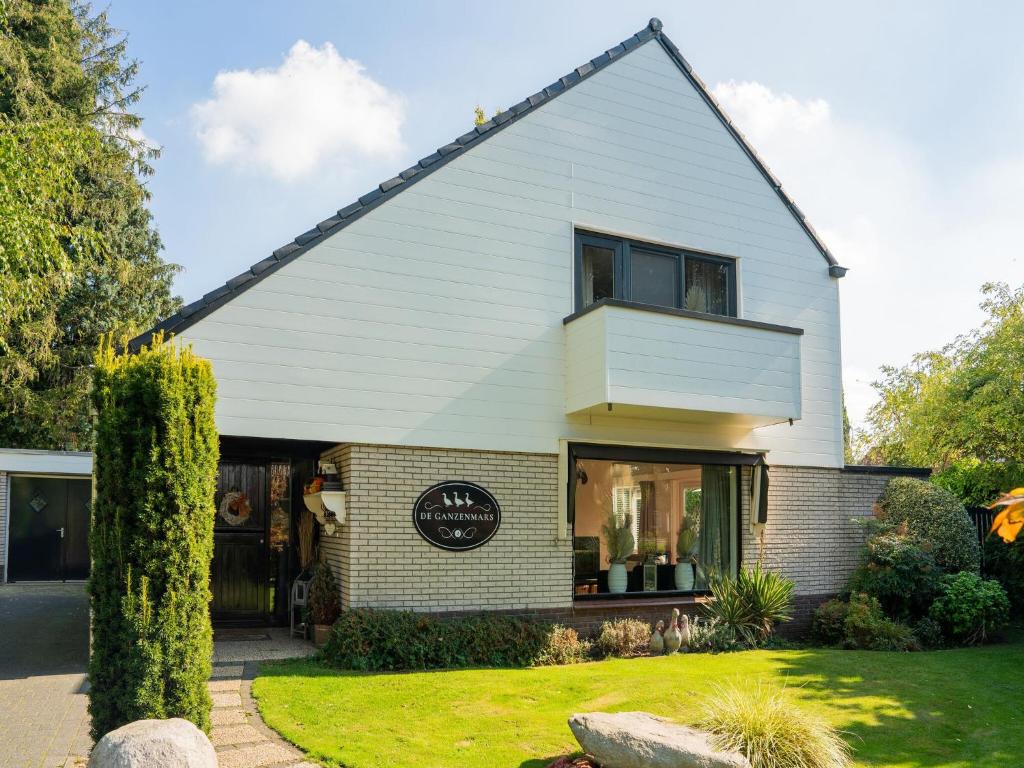 Una casa blanca con un cartel en la parte delantera. en Cozy villa with wellness tub sauna and garden, en Den Ham