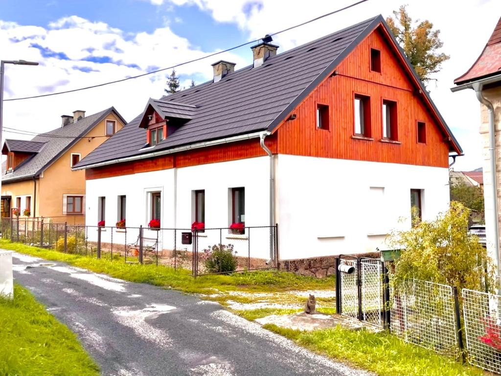 una casa blanca y naranja con techo negro en Za řekou, en Mladé Buky