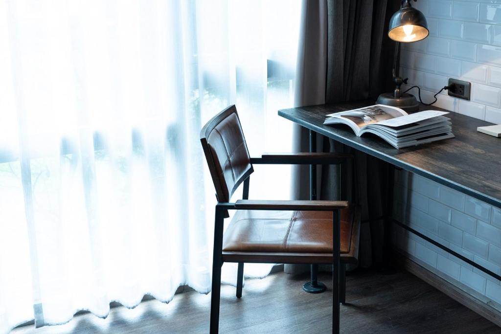 A compact work desk beside a bright curtained window.