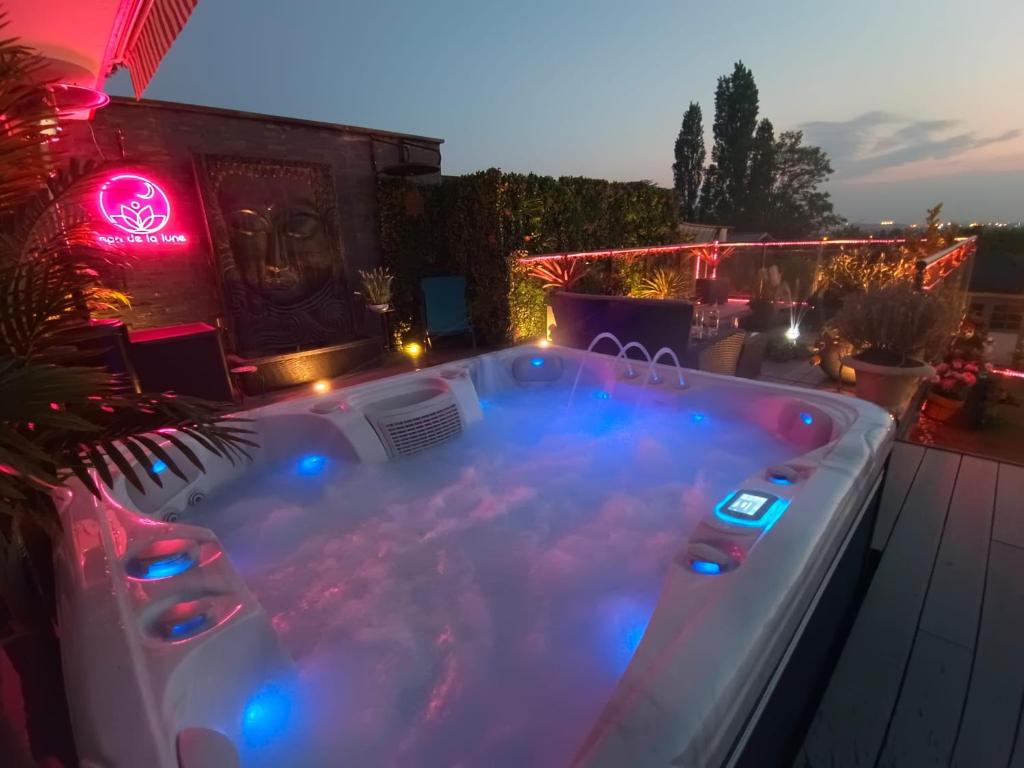 a hot tub on the roof of a house at night at Spa de la Lune - Private love room suite with terrace and view - Air Conditioned- Double jacuzzi - Sauna - King size bed - Free WIFI - Free parking - Free breakfast - Close to CDG airport and to the North of Paris in Clichy-sous-Bois