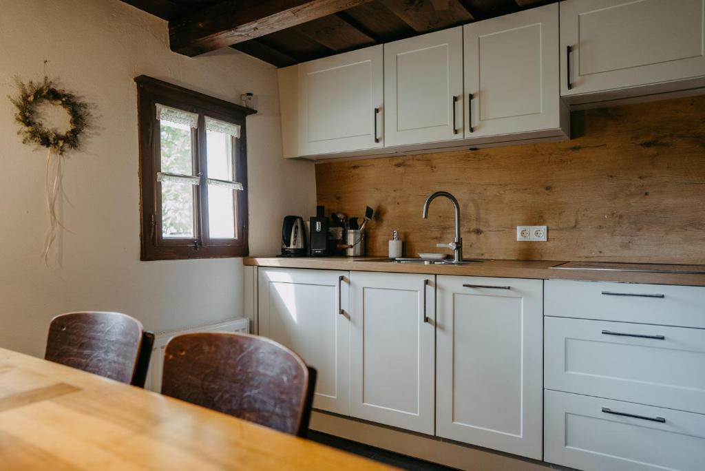 a kitchen with white cabinets and a wooden table at Kellerstöckl Berg 106 in Strem