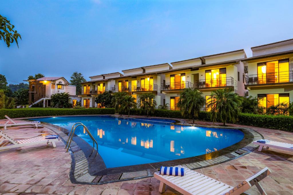 a swimming pool in front of a building at Corbett Panorama Resort in Rāmnagar