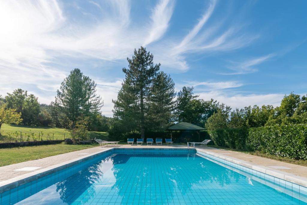 een zwembad in een tuin met bomen en een hemel bij Casale Falco Grande in Chiusi della Verna