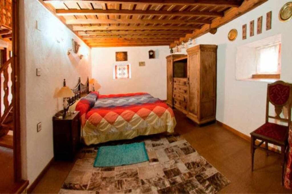 um quarto com uma cama, uma mesa e uma cadeira em Casa Tía Modesta es una cálida y acogedora casa rural em Cabezas Bajas