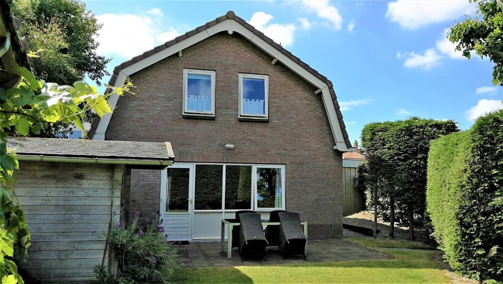a house with a table and chairs in the yard at Vakantiehuis Domburg 100 meter van het strand - veel privacy - eigen parkeerplaats. in Domburg