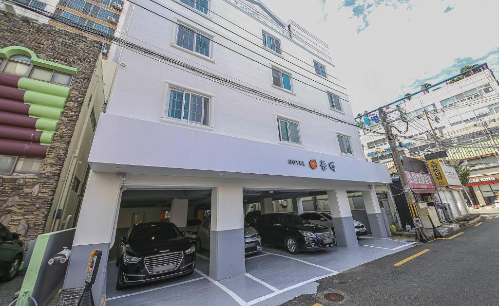 コジェにあるGeoje Dongbeck Hotel Gohyeonの車二台駐車した白い建物