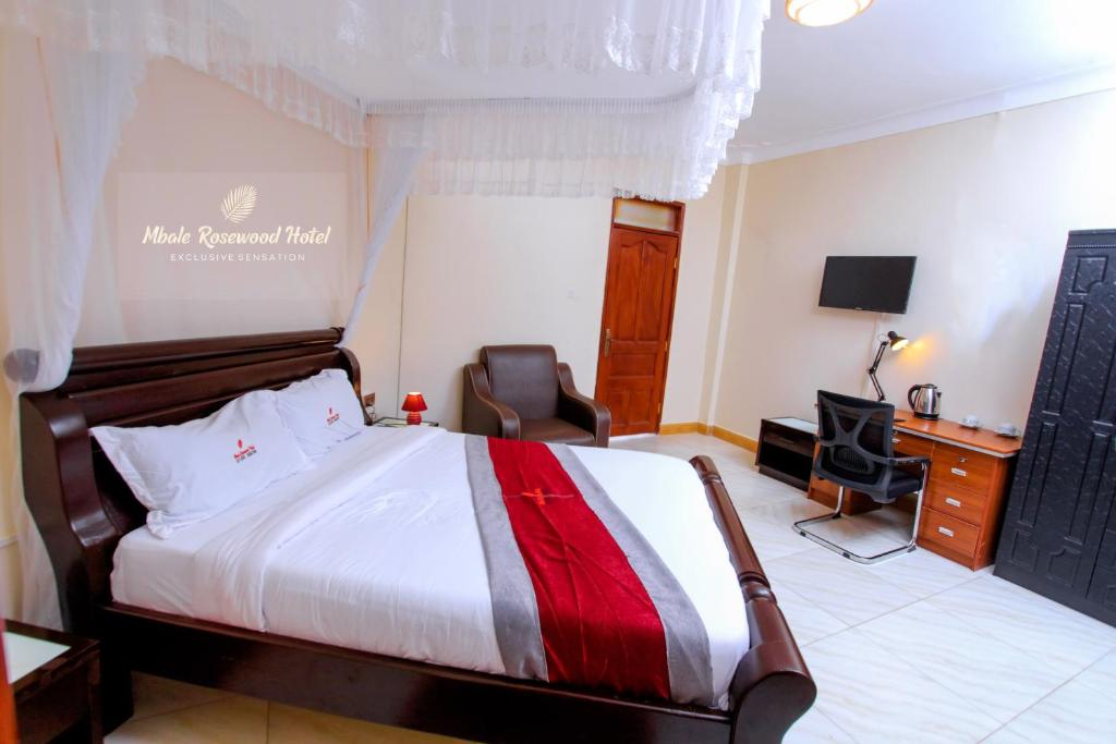 a hotel room with a bed and a desk and chair at Mbale Rosewood Hotel in Mbale