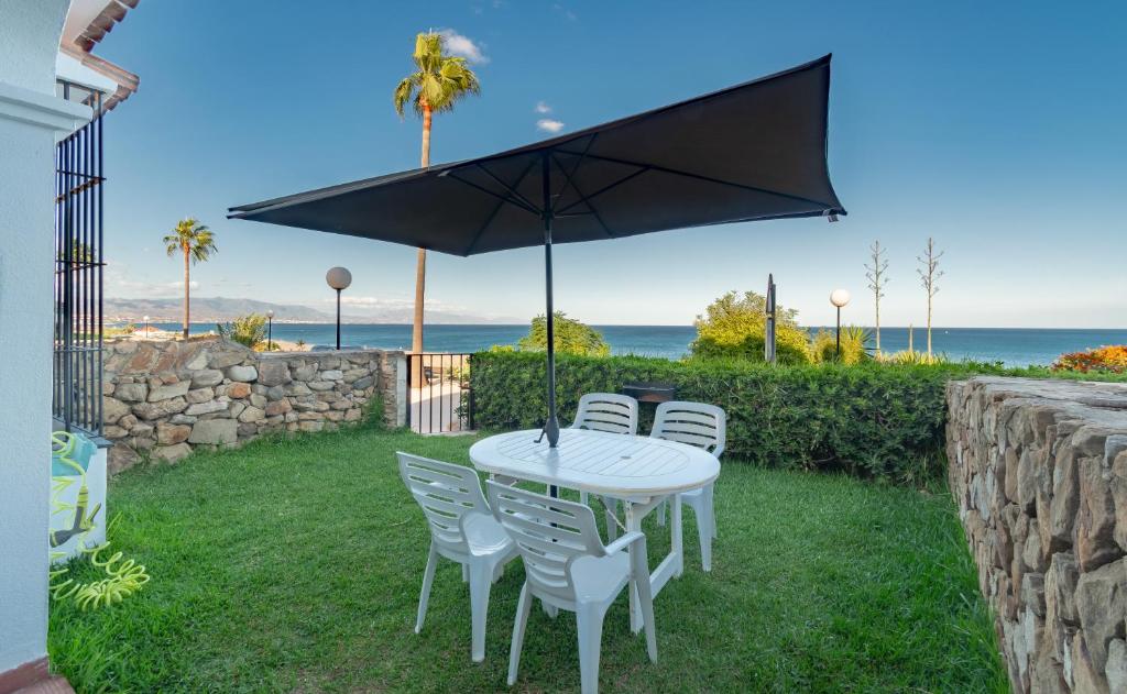 einen weißen Tisch und Stühle mit Sonnenschirm in der Unterkunft Aldea Beach 39 - Fantástica casa a pie de playa in Manilva