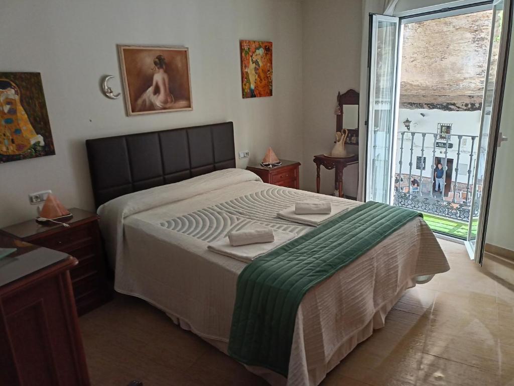 sypialnia z dużym łóżkiem i dużym oknem w obiekcie La Casa Del Rio w mieście Setenil