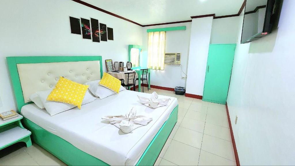 a bedroom with a bed with yellow and white pillows at Demiren Hotel in Cagayan de Oro