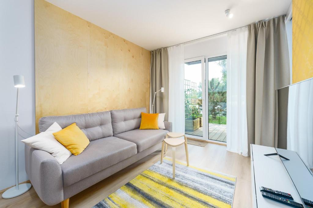 德茲維濟諾的住宿－Apartament BIRCH TREE SurfingBird Dźwirzyno，客厅配有灰色的沙发和黄色的枕头。