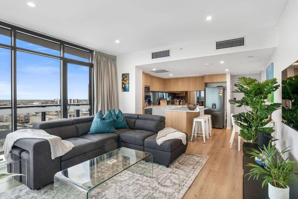 a living room with a couch and a kitchen at Stunning Views 2BR Luxury Pool Parking Gym WiFi in Adelaide