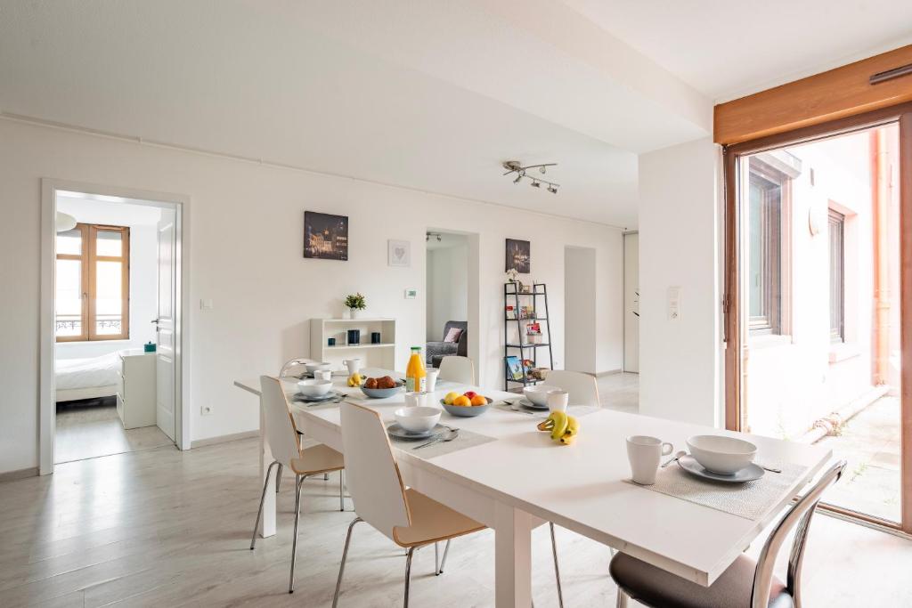 - une salle à manger blanche avec une table et des chaises blanches dans l'établissement Le Manoir de Cyrielle - WIFI - 20 min centre ville de Strasbourg, à Bischheim