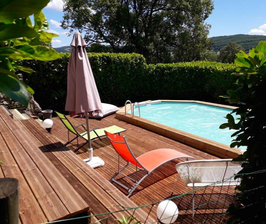 een parasol en stoelen op een terras naast een zwembad bij Maison de 4 chambres avec piscine privee jardin clos et wifi a Pierrefiche in Pierrefiche