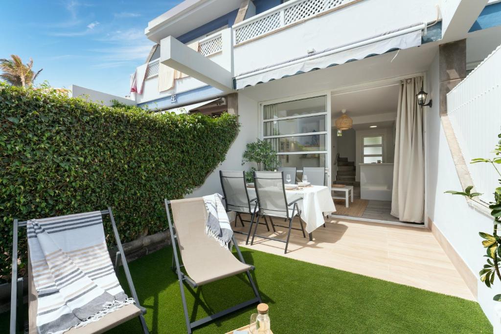 un patio con mesa y sillas en una casa en Barefoot Bungalow en Maspalomas