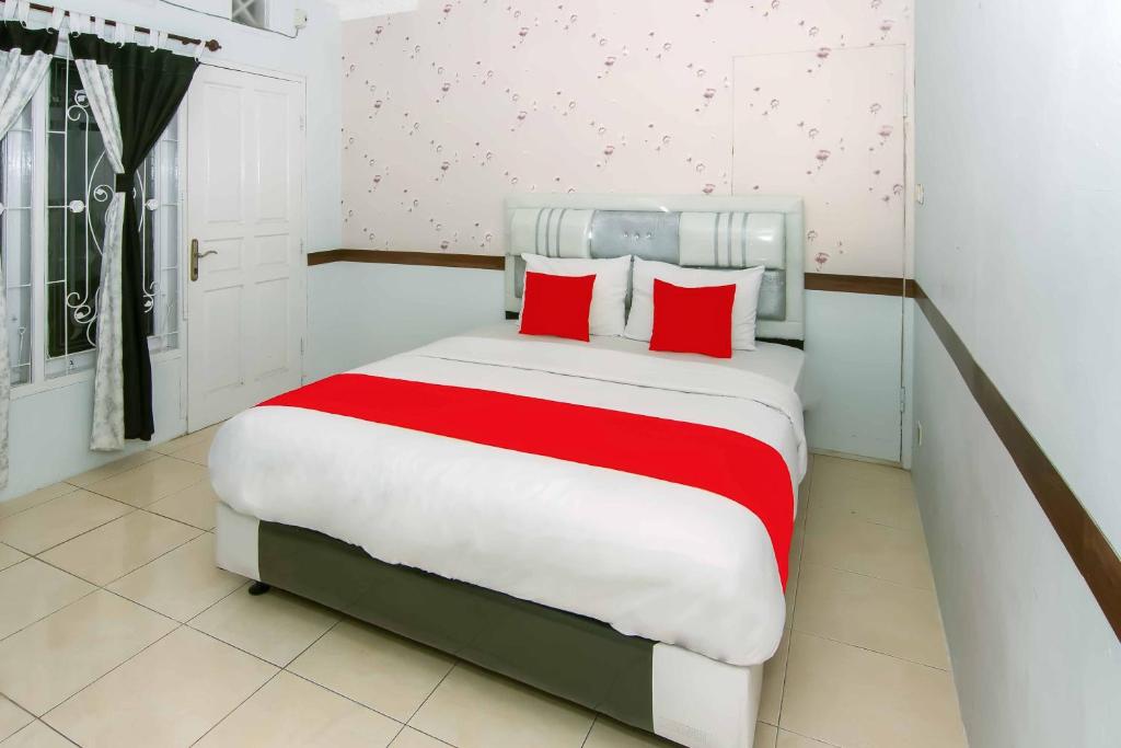 Un dormitorio con una cama grande con almohadas rojas. en Zazadior Residence Syariah near Pantai Padang Mitra RedDoorz, en Padang
