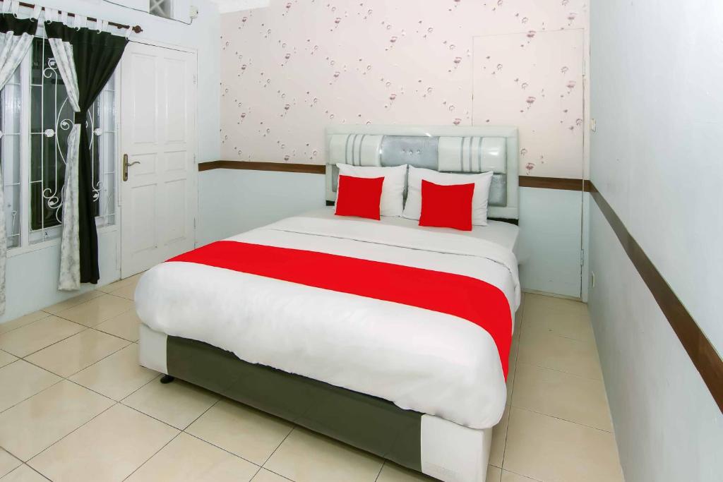 a bedroom with a large bed with red pillows at Zazadior Residence Syariah near Pantai Padang Mitra RedDoorz in Padang