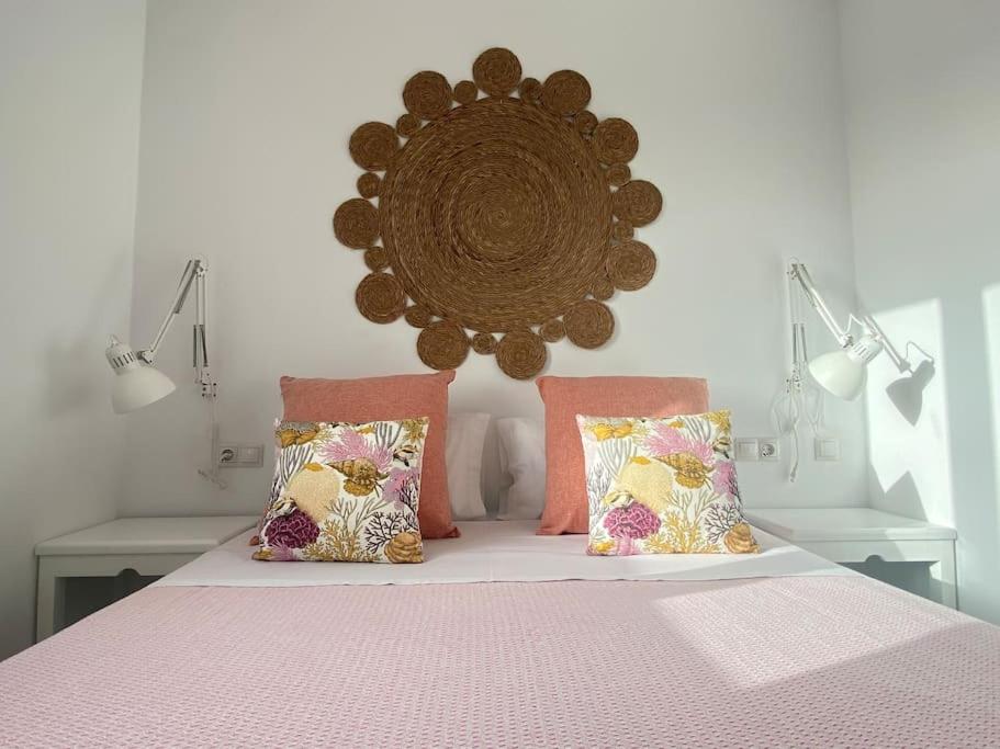 Schlafzimmer mit einem Bett mit rosa Bettwäsche und Kissen in der Unterkunft La Casa de las Hespérides in Morro del Jable