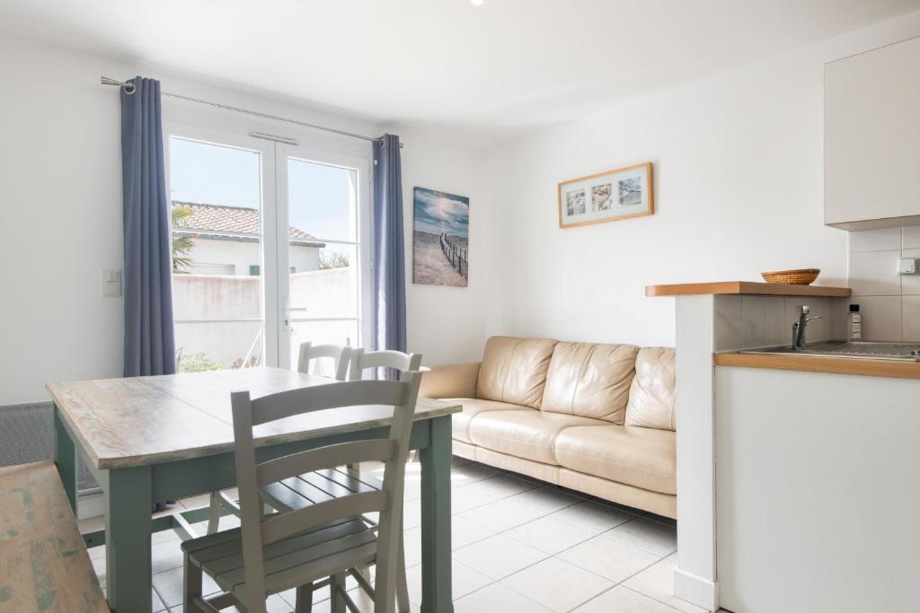 uma cozinha e sala de estar com uma mesa e um sofá em Appartement Colombelle proche du marché et de la plage em La Couarde-sur-Mer