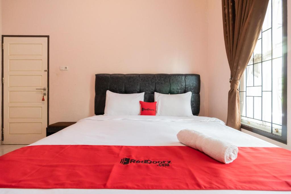 Un dormitorio con una cama grande con una manta roja. en RedDoorz Syariah at D'Ostha Residence, en Bukittinggi
