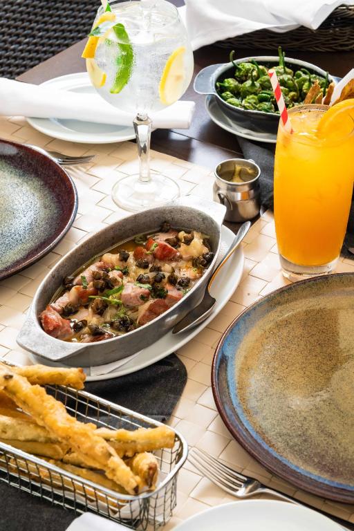 a table with dishes of food and a drink at Pestana Cidadela Cascais - Pousada & Art District in Cascais