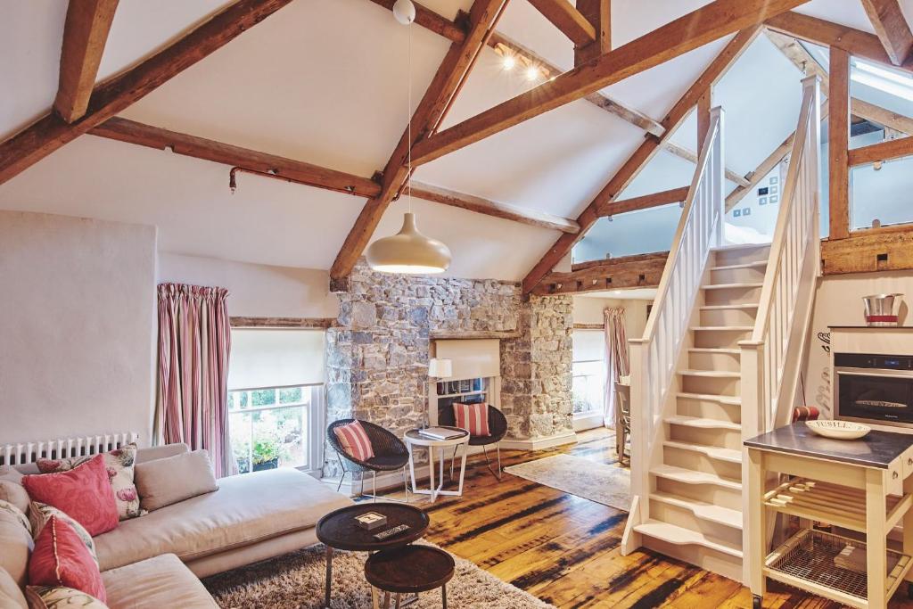 a living room with wooden ceilings and a staircase at Lotus Cottage in Rhoose