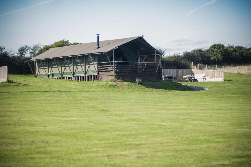 a large building on a grass field with a fence at Whiteford - Safari Glamping Tent - Llangennith in Llangennith
