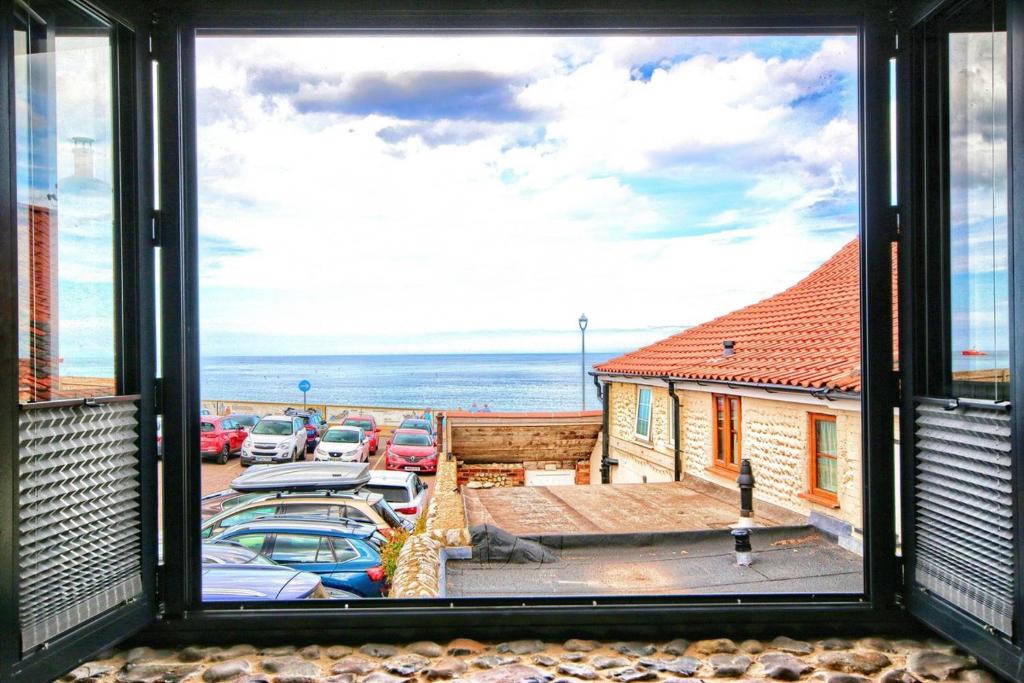 een raam met uitzicht op een parkeerplaats bij Sea Spray in Sheringham