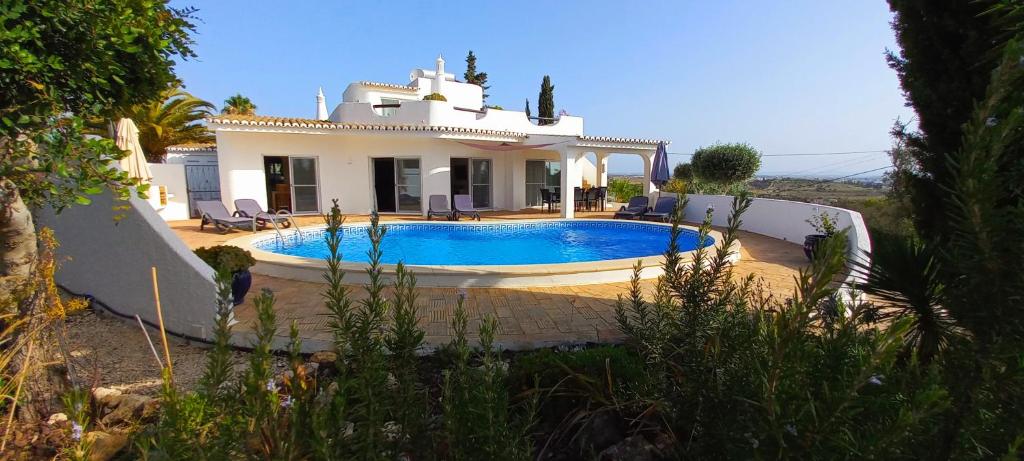 a villa with a swimming pool in front of a house at Casa Gemeas in Carvoeiro