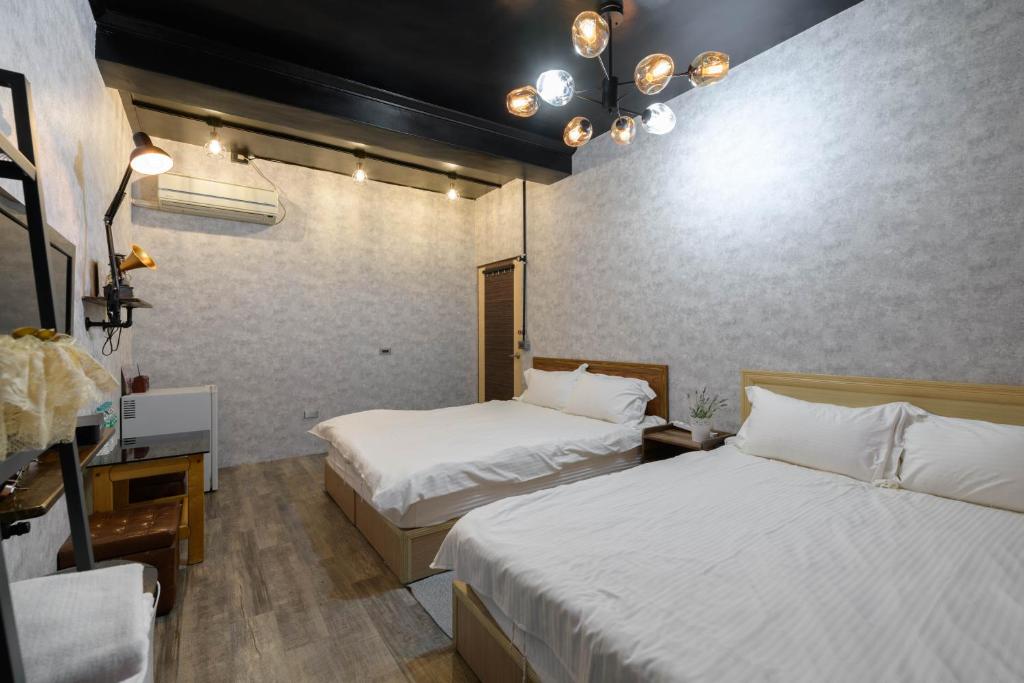 a hotel room with two beds and a desk and lights at 羅東小宅一生 in Luodong