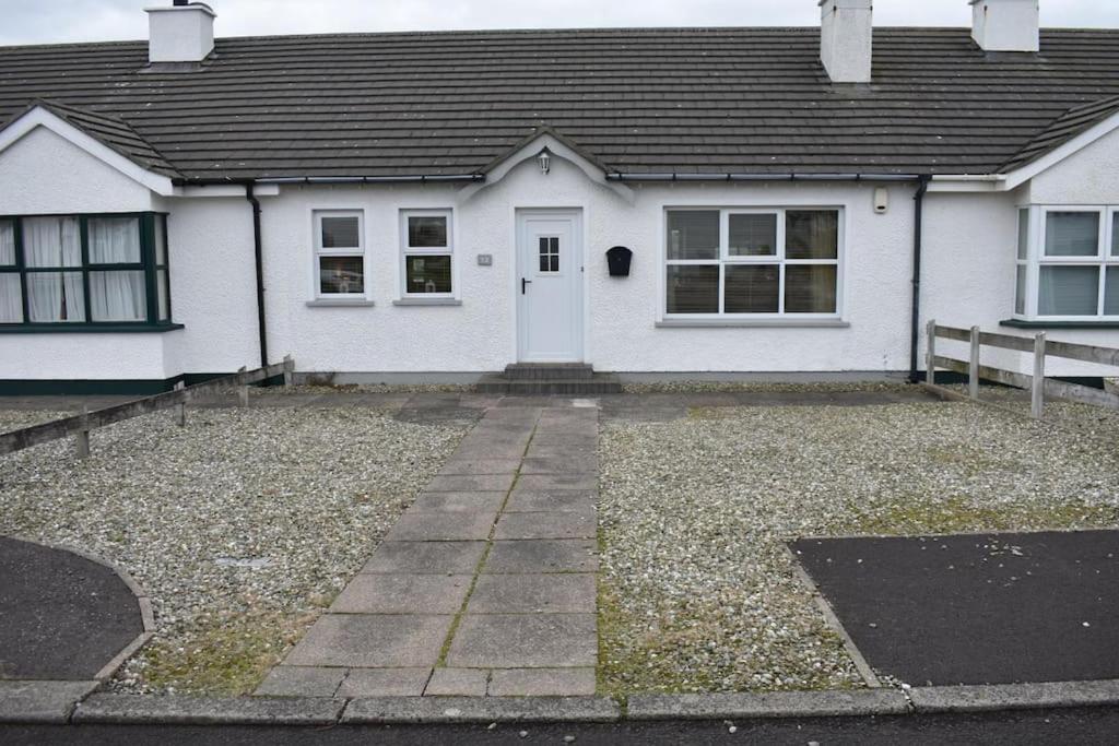 a white house with a driveway in front of it at Holiday Home- Portballintrae in Portballintrae