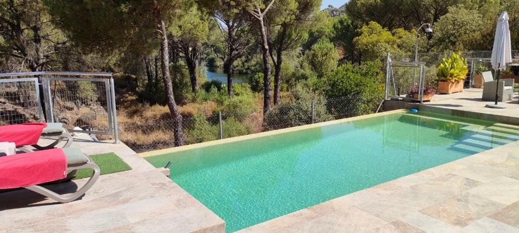 een zwembad met 2 stoelen en een tafel bij CABAÑA DE MADERA JUNTO AL LAGO LAS JARAS in Córdoba