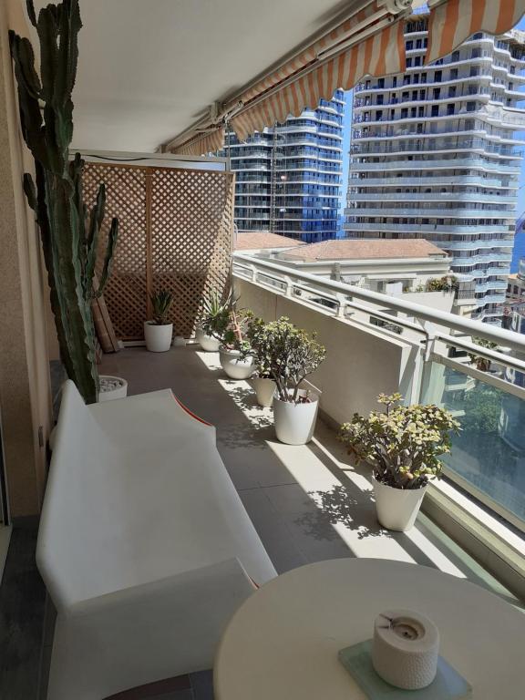 a balcony with a white couch and potted plants at Vue mer aux portes de Monaco in Beausoleil