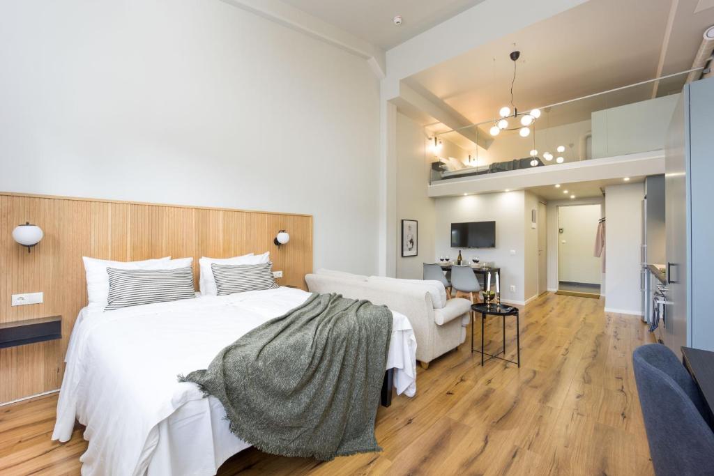 um quarto com uma grande cama branca e uma cadeira em Foundry Hotel Apartments em Uppsala