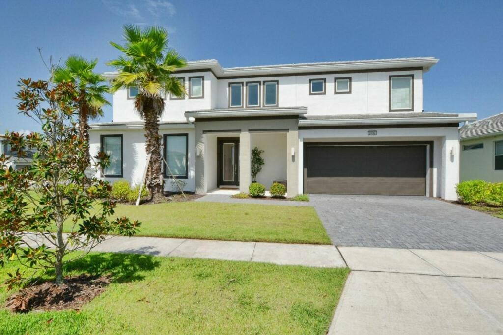 a large white house with a palm tree at Sonoma Resort 7 Bedroom Vacation Home 2600YA in Kissimmee