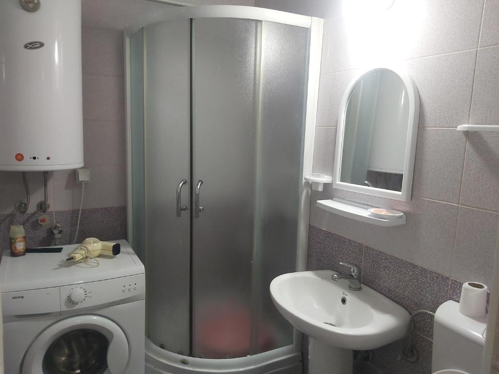 een badkamer met een douche, een wastafel en een wasmachine bij MIA apartment in Skopje