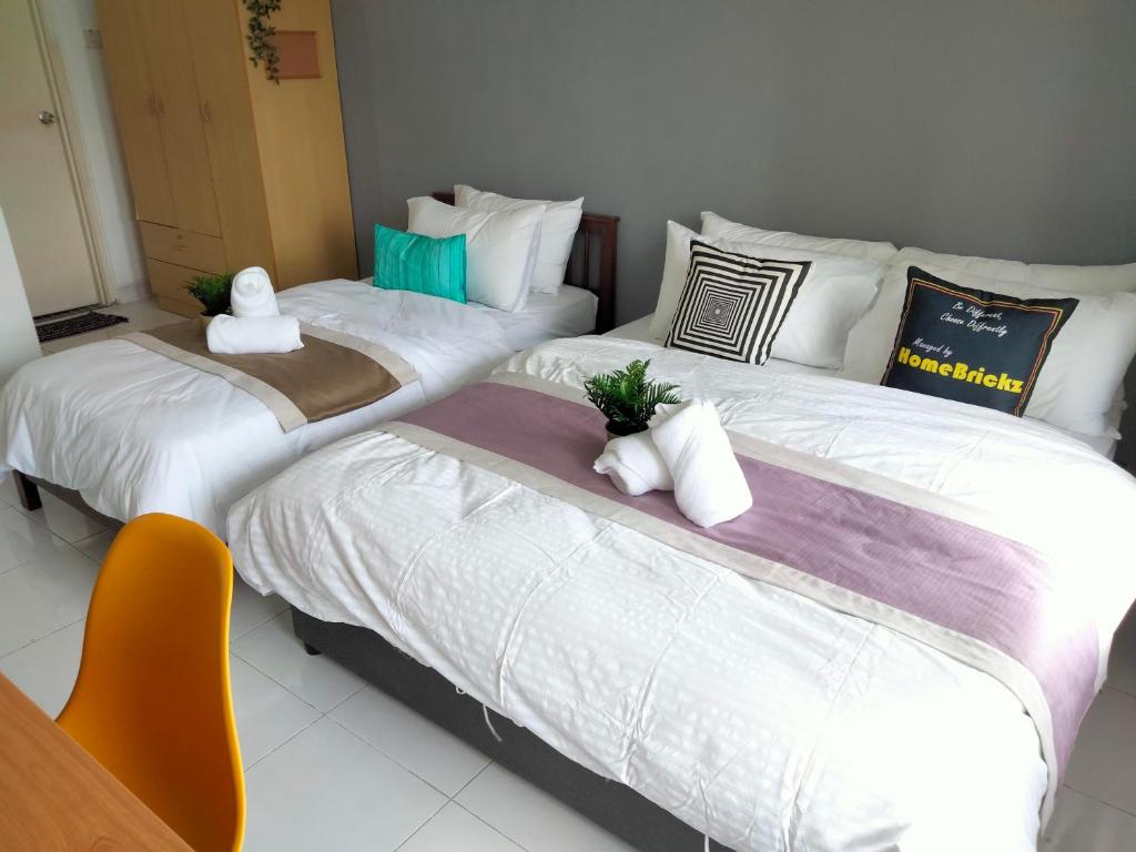 três camas num quarto com uma cadeira laranja em Cyberia Crescent - 3 bedroom 8 Pax em Cyberjaya