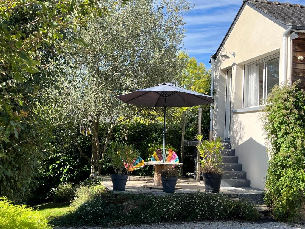 un patio con mesa y sombrilla en Chambre d’hotes golf du Morbihan, en Plougoumelen