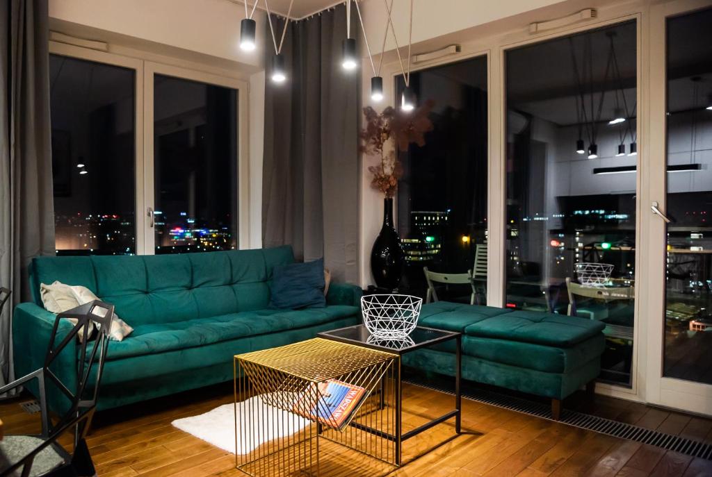 sala de estar con sofá verde y ventana grande en Qbik Artistic Cityscape Apartment, en Varsovia