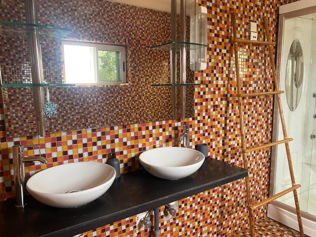 een badkamer met twee wastafels op een zwart aanrecht bij L'Oasis Guesthouse in Cotonou