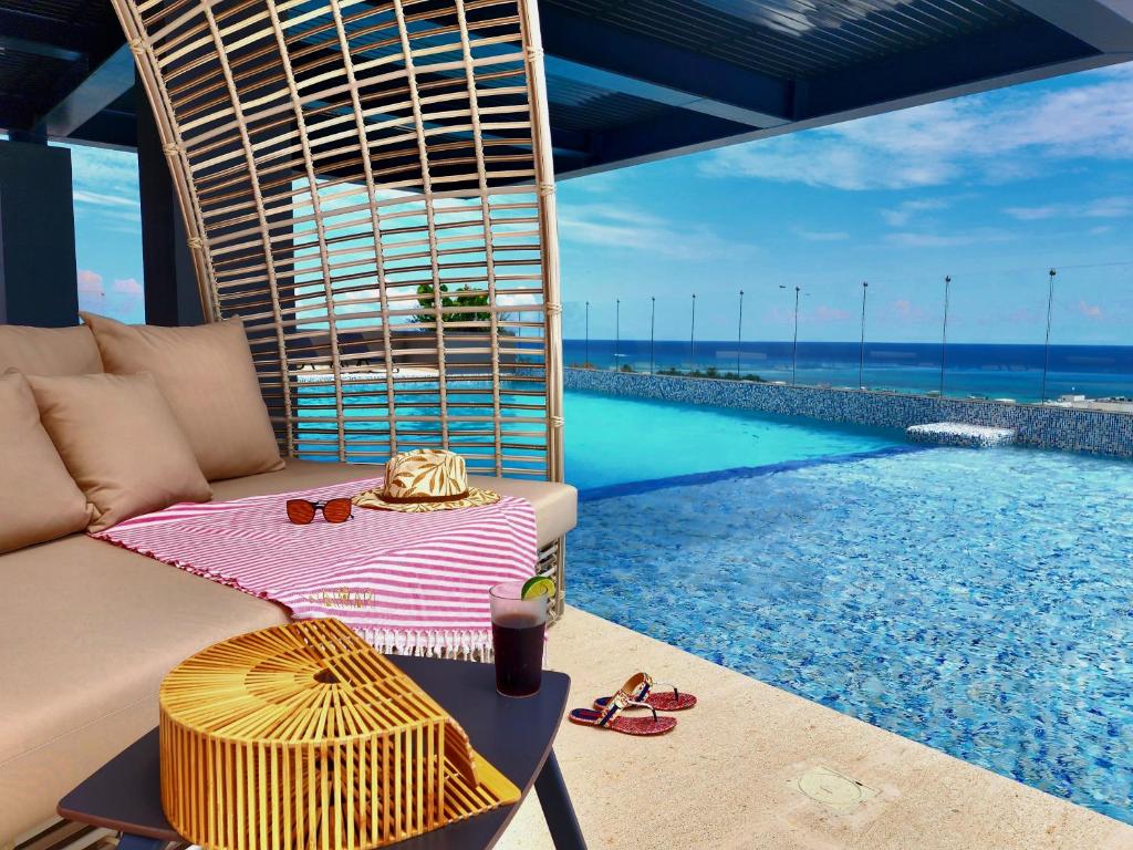een woonkamer met een bank en een zwembad bij Singular Dream Beach Residences in Playa del Carmen