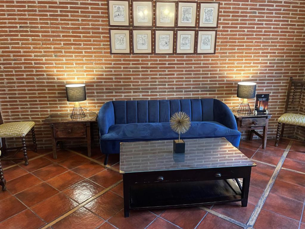 a living room with a blue couch and two tables at Hotel Arco San Vicente in Ávila