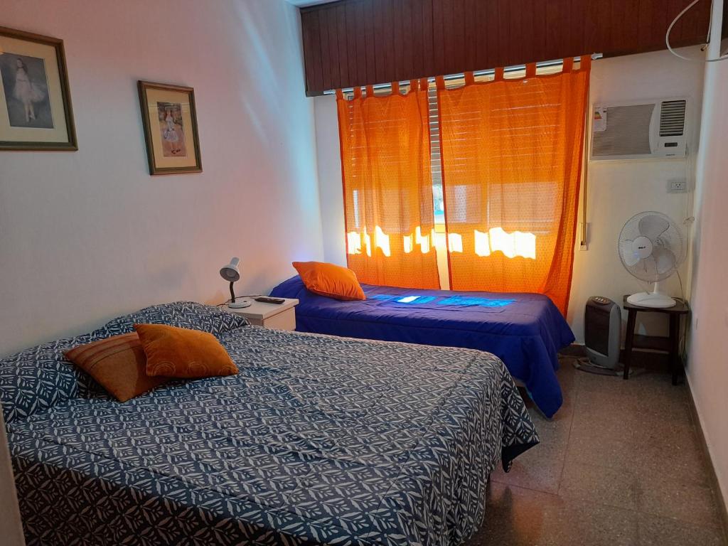 een slaapkamer met 2 bedden en een oranje raam bij IRUÑA CENTRO- 150 mts peatonal de Resistencia in Resistencia