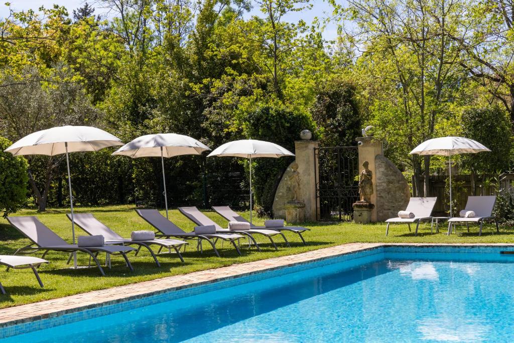 a pool with lounge chairs and umbrellas next to at La Magdeleine - Mathias Dandine in Gémenos