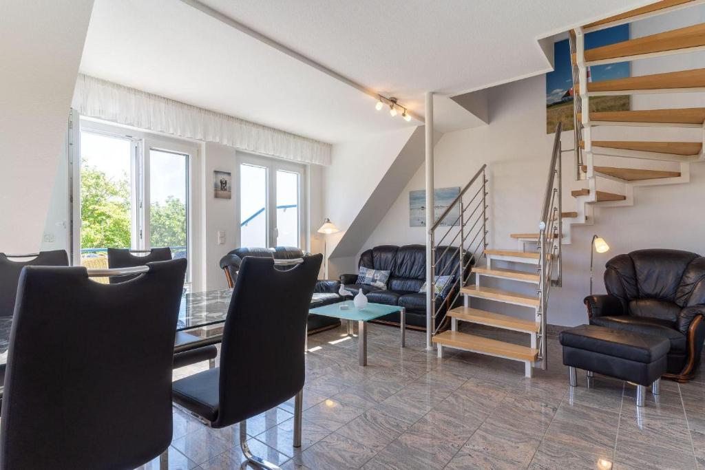 uma sala de estar com cadeiras, uma mesa e escadas em Haus-Eriel-OG-links em Brösum