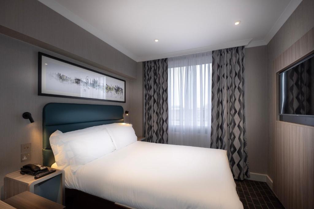 a bedroom with a large white bed and a window at City Sleeper at Royal National Hotel in London